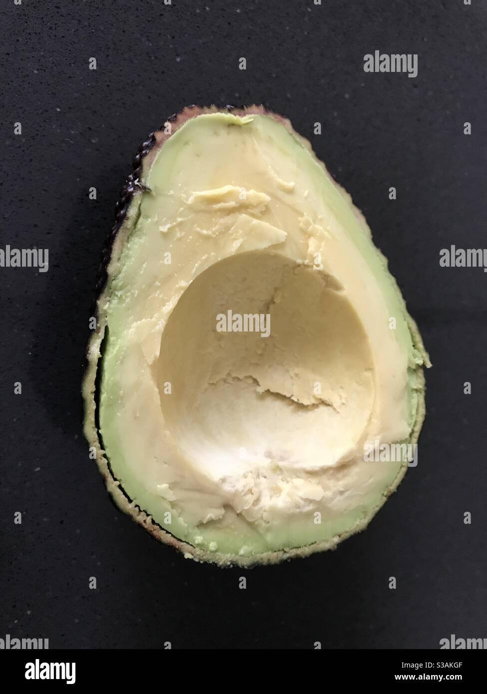 Avocado pear half against a dark background - Smartphone Captured Stock Image