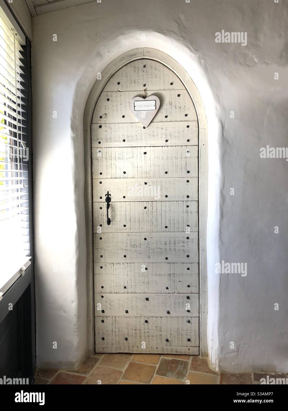 Arched door with white washed wooden panels inside a farmhouse - Smartphone Captured Stock Image
