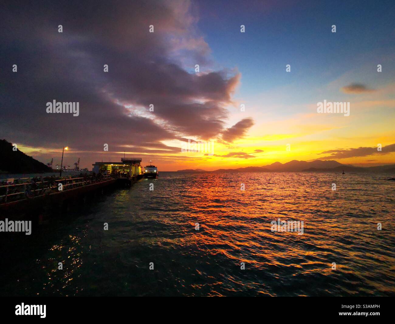 A beautiful sunset over the Yung shue wan pier on Lamma island in Hong kong. - Smartphone Captured Stock Image