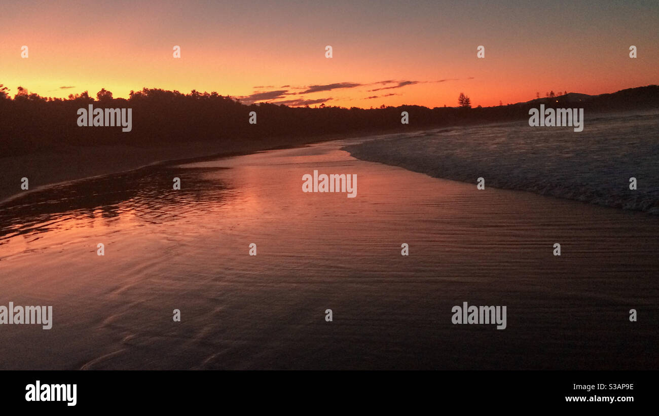 Serene sunset, orange and pink sky reflected in the shimmering water at the beach, Australia - Smartphone Captured Stock Image