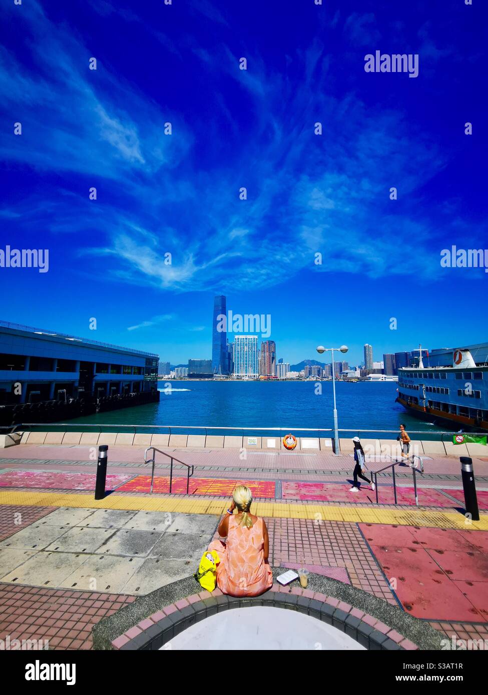 a woman enjoying the views of Victoria harbour and western kowloon district. - Smartphone Captured Stock Image