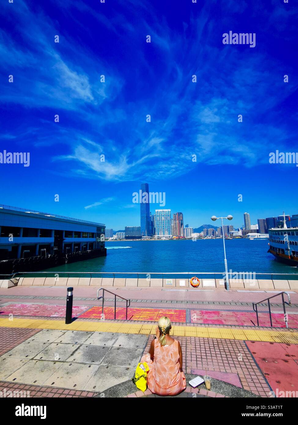za woman enjoying the views of Victoria harbour and western kowloon district. - Smartphone Captured Stock Image