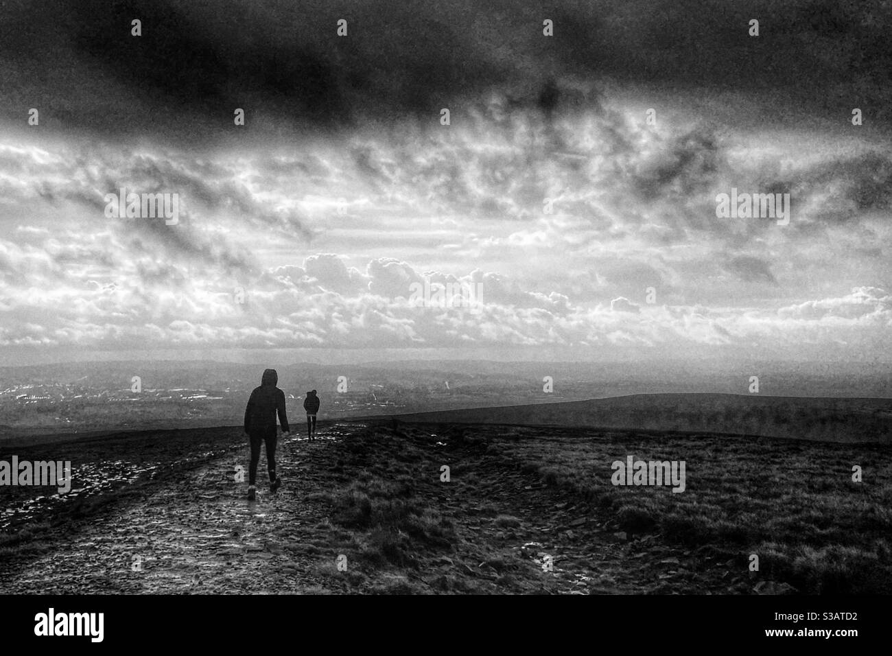 Two people walking in wind and rain on the to of Pendle Hill in Lancashire Stock Photo