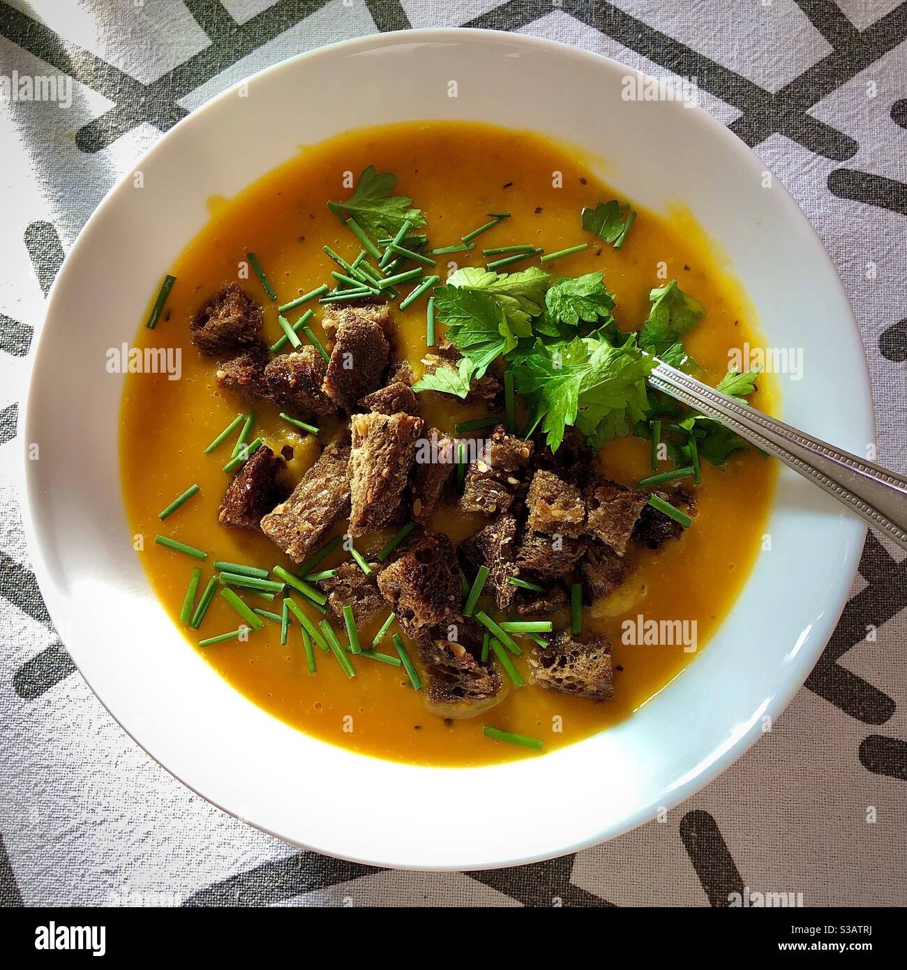 Pumpkin and potato soup with croutons, chives and parsley. Stock Photo