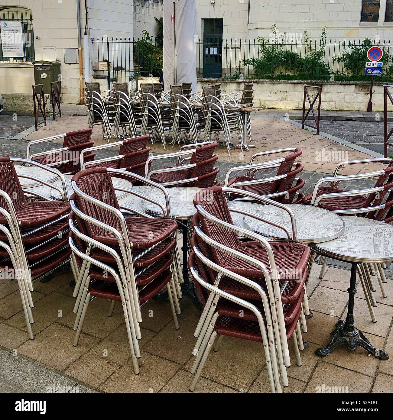 Stacked café chairs and tables due to closed business during Covid-19 lockdown in France. - Smartphone Captured Stock Image
