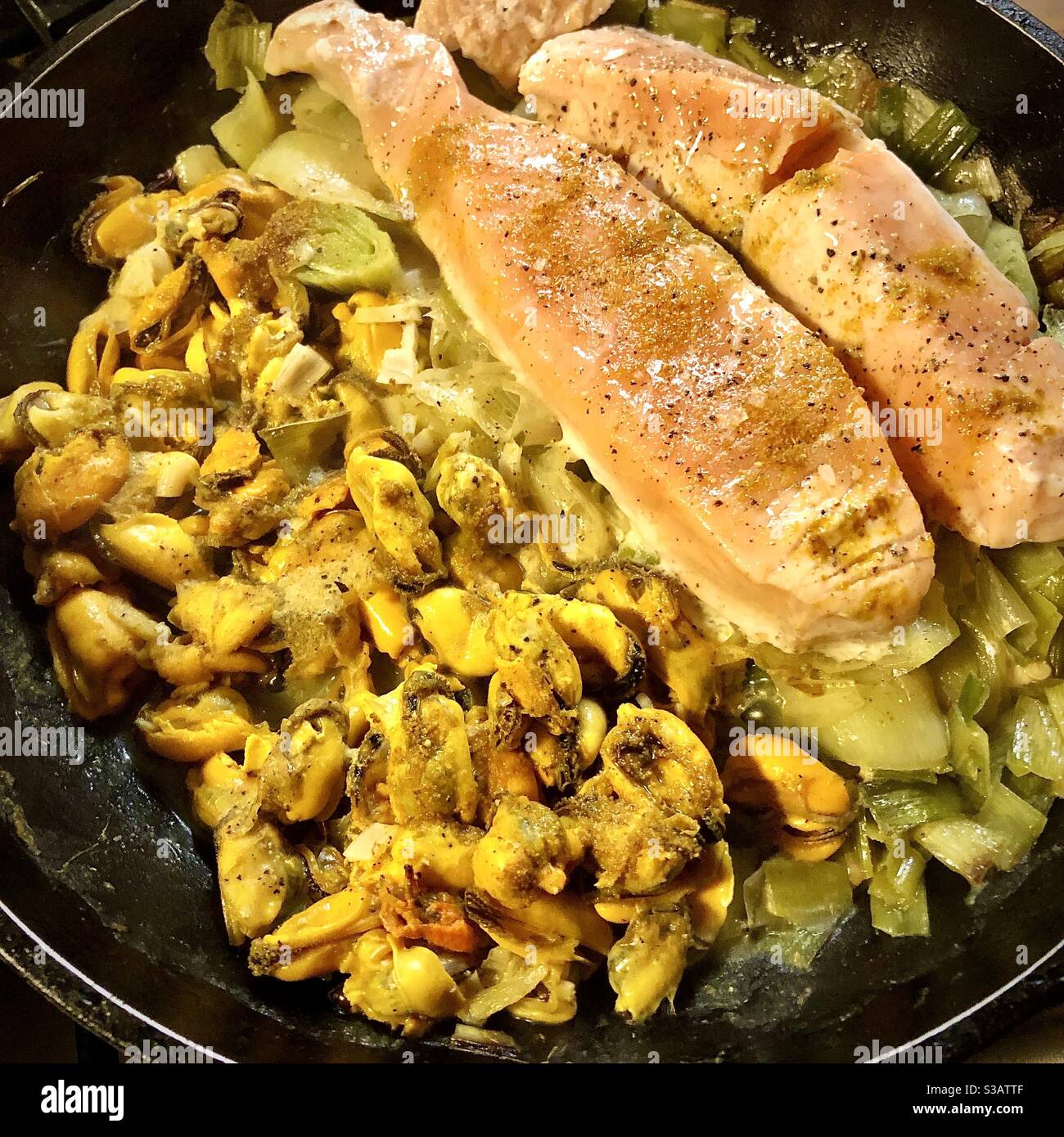 Healthy hot meal of fresh salmon and mussels with leeks. Stock Photo