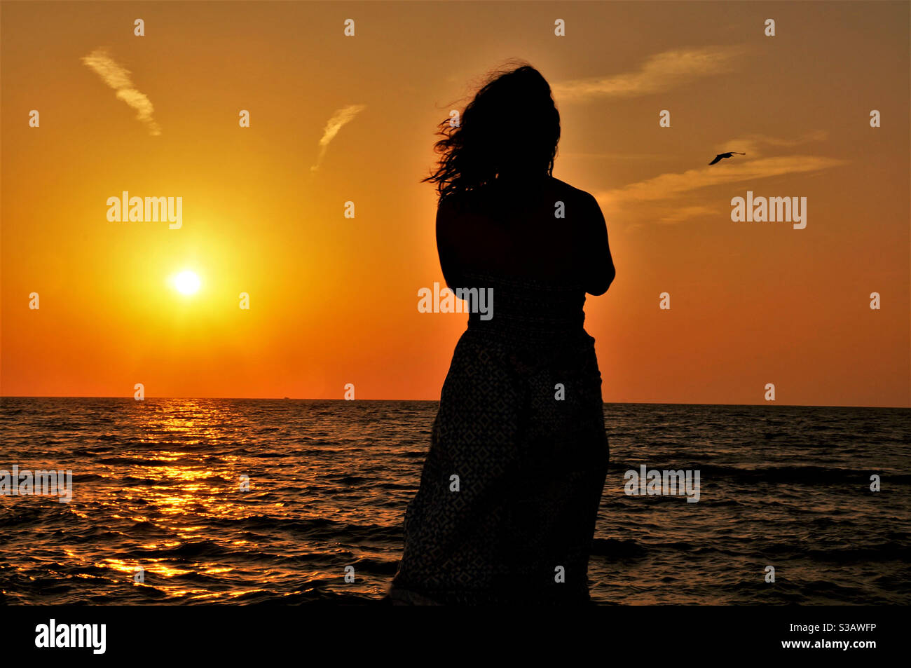 Silhouette of a young woman by the sea at sunset - Smartphone Captured Stock Image