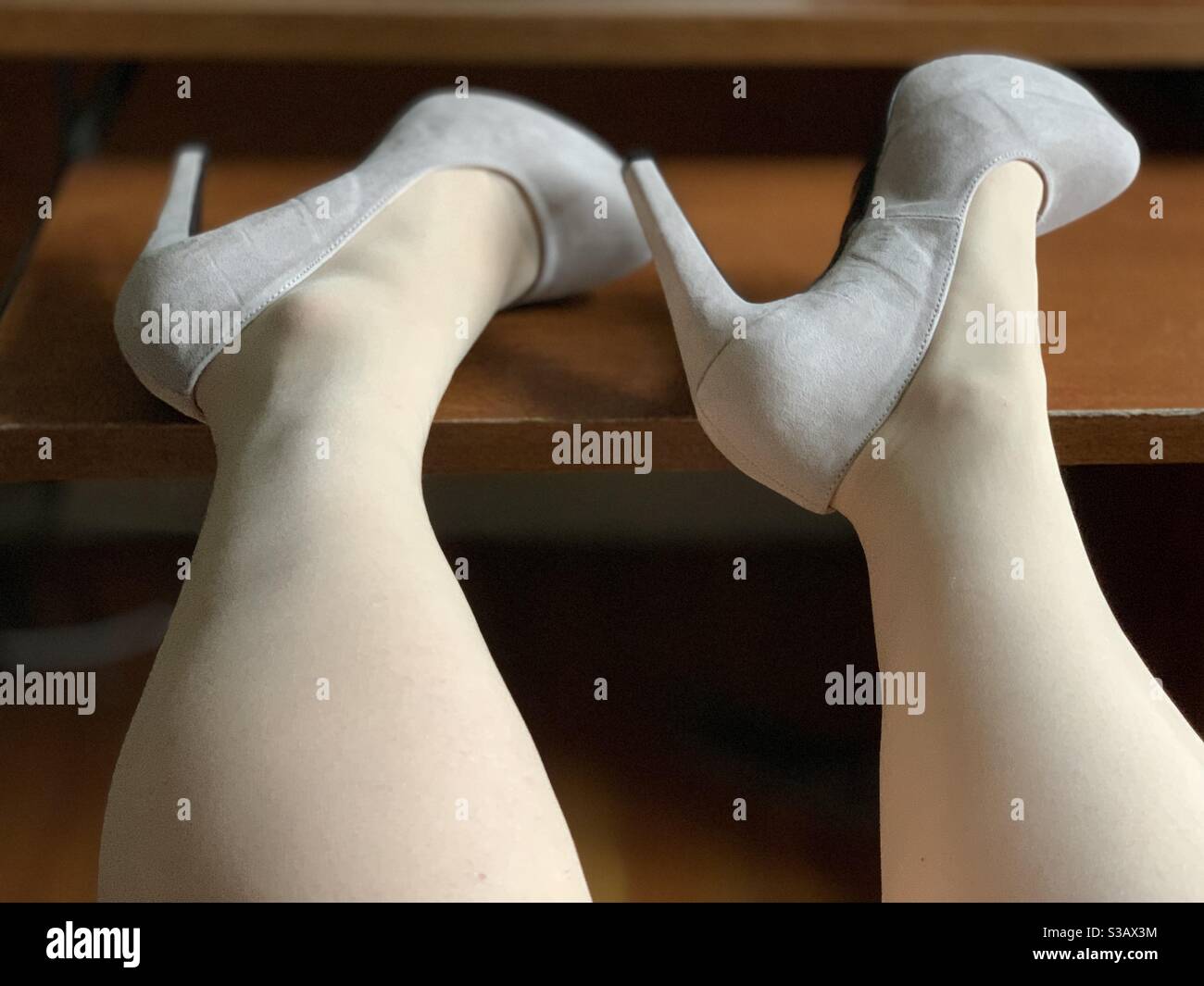 A woman’s stocking-clad legs and high heels on a desk - Smartphone Captured Stock Image