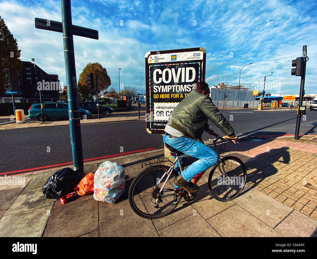 A man cycles past a sign highlighting Covid-19 testing on Bromley Road, London November 31 - Smartphone Captured Stock Image