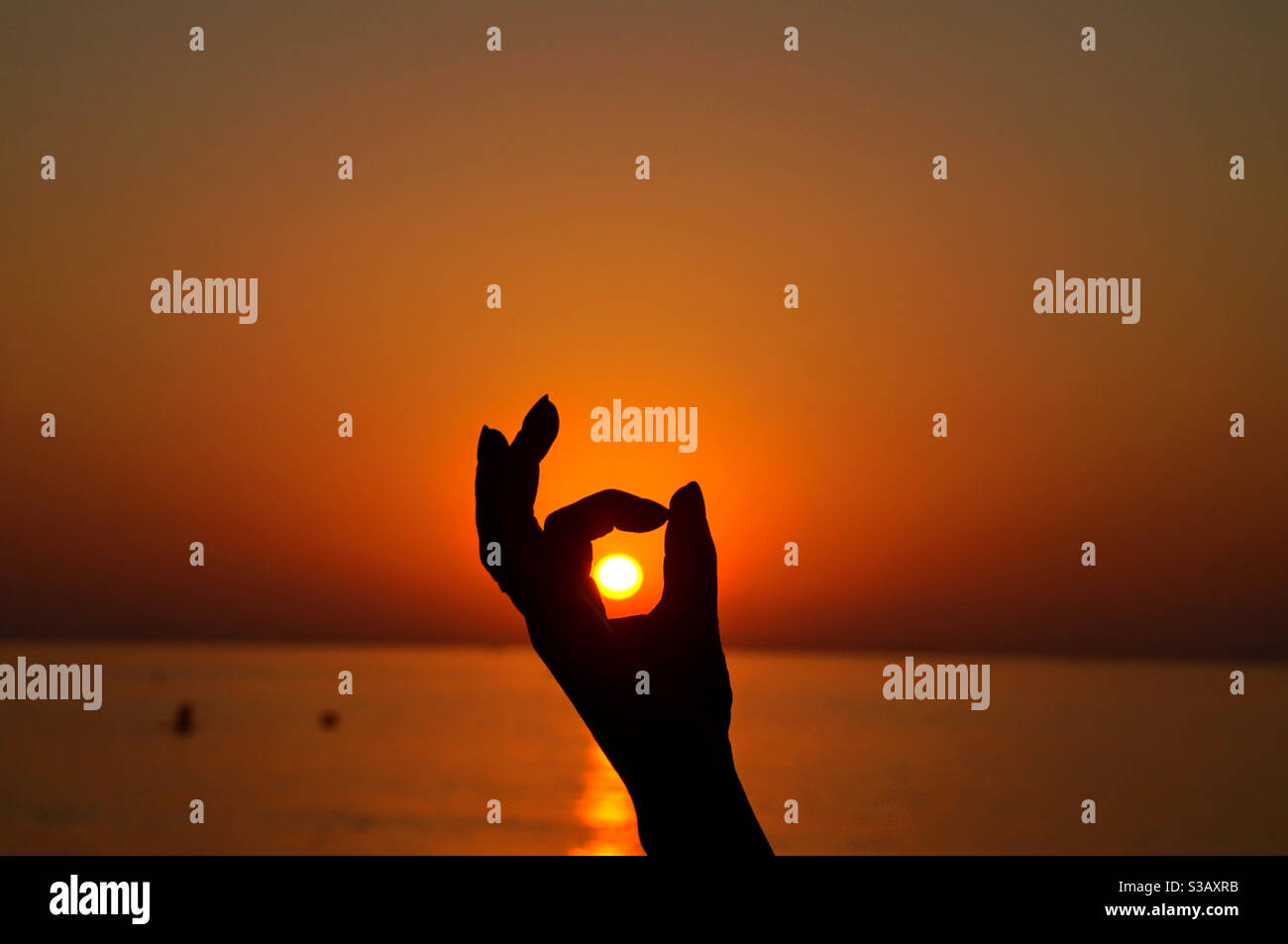Silhouette of a hand and a beautiful sun at sunset - Smartphone Captured Stock Image