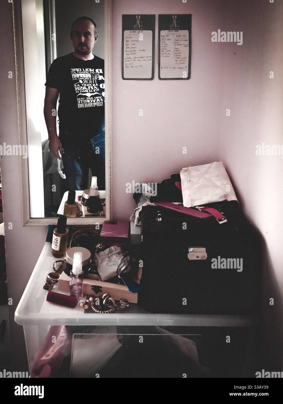 Reflection in a mirror of a man entering a bedroom with items left on top of a plastic box. - Smartphone Captured Stock Image