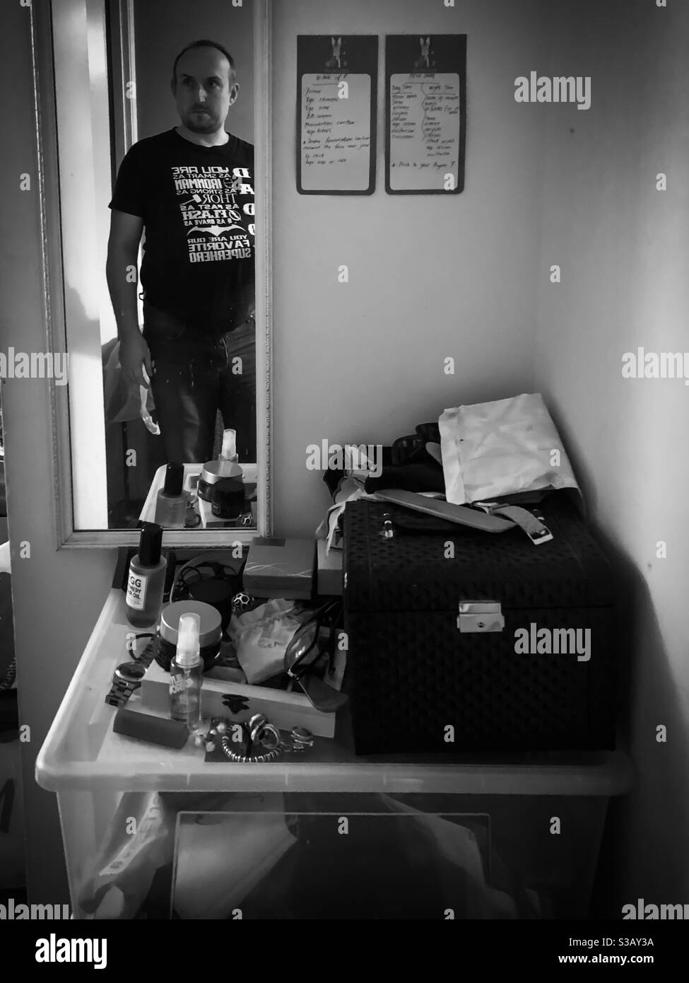 Reflection in a mirror of a man entering a bedroom with items left on top of a plastic box. - Smartphone Captured Stock Image