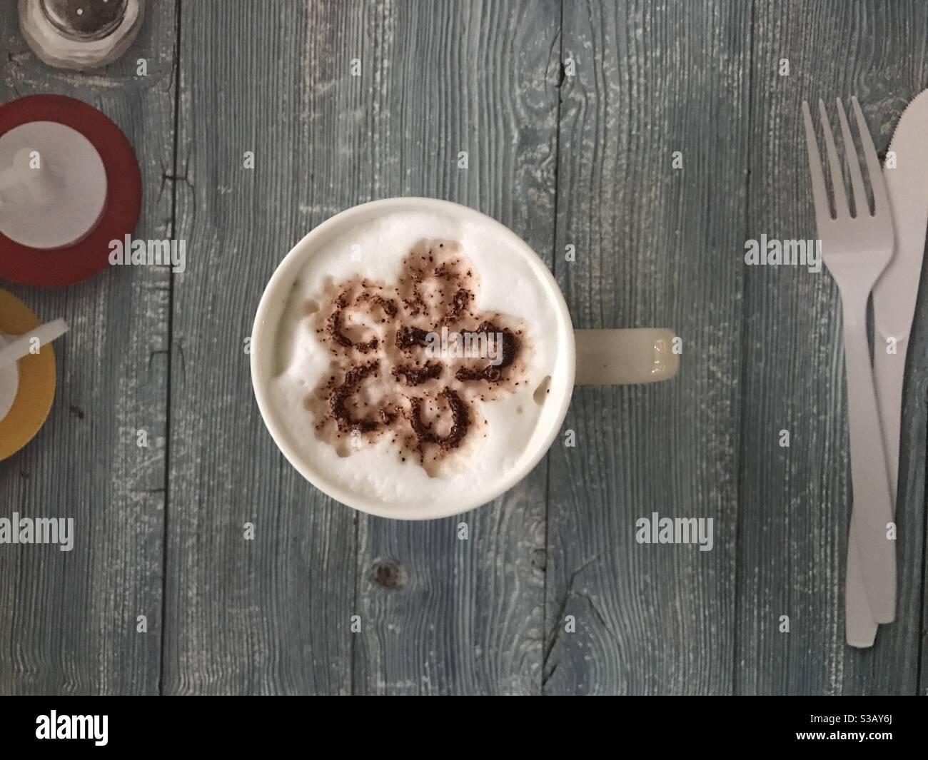 Flower shaped design on a cup of cappuccino coffee - Smartphone Captured Stock Image
