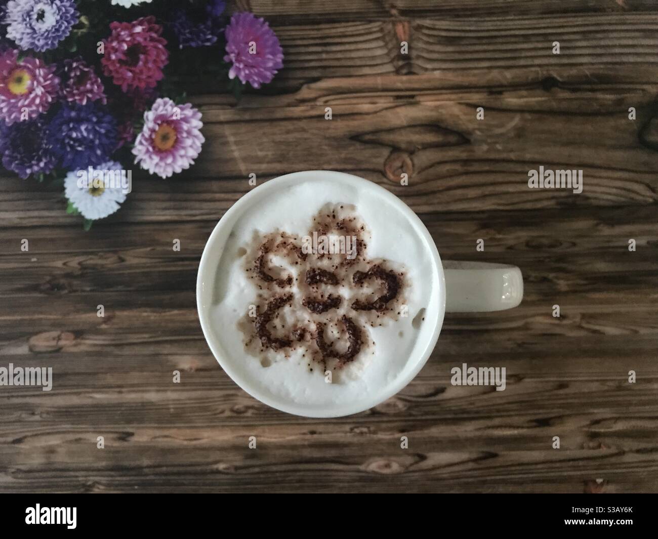 Flower shaped design on a cup of cappuccino coffee - Smartphone Captured Stock Image