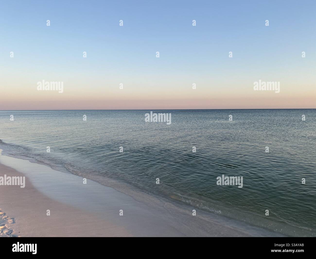 Soft pastel sunset skies over calm Gulf of Mexico emerald colored water ...
