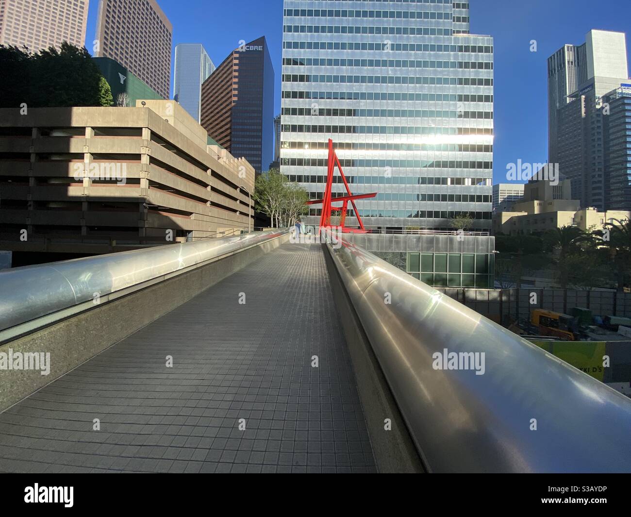 LOS ANGELES, CA, JUL 2020: wide view bright red, steel sculpture 'Shoshone' by Mark DiSuvero, 1982, in front of the Citigroup Center in Downtown, viewed from pedestrian bridge - Smartphone Captured Stock Image