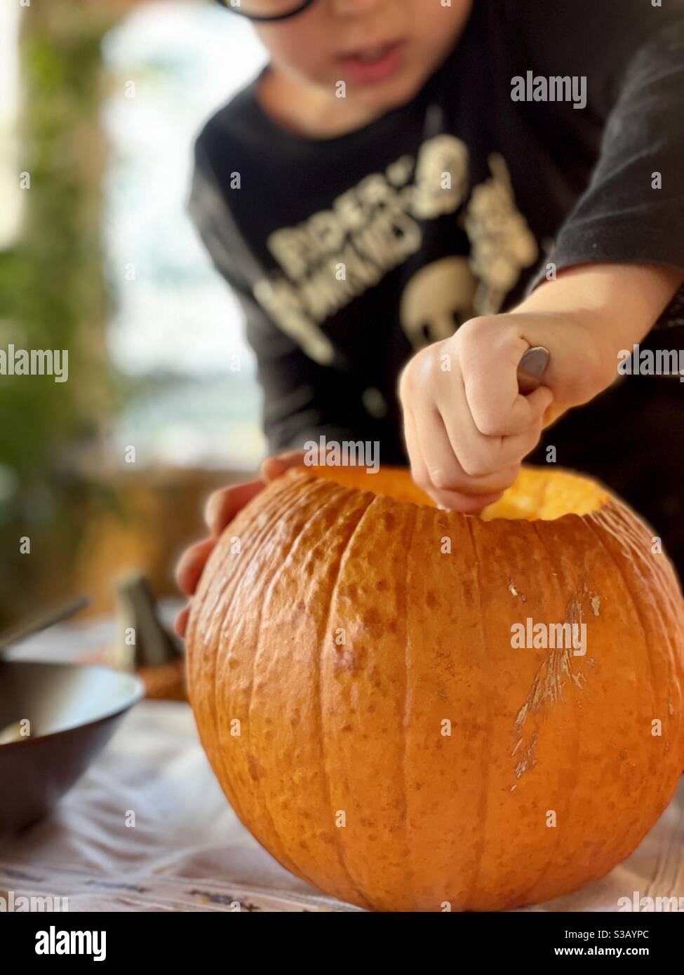 Boy scooping out the inside flesh of a pumpkin in preparation for Halloween Stock Photo