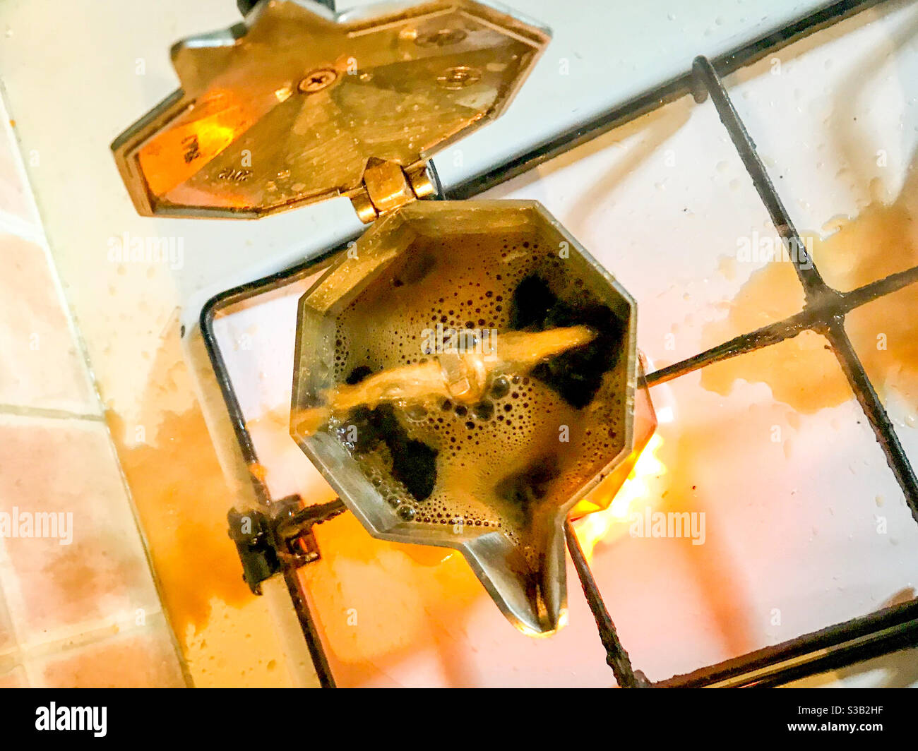 moka coffee with boiling coffee coming out on the kitchen stove with gas flame, top view - Smartphone Captured Stock Image
