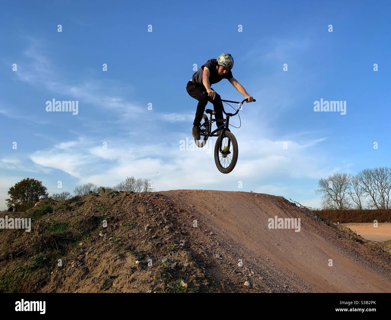 A man jumps his BMX bicycle while riding an off-road course near Fleet in Hampshire, England. Stock Photo
