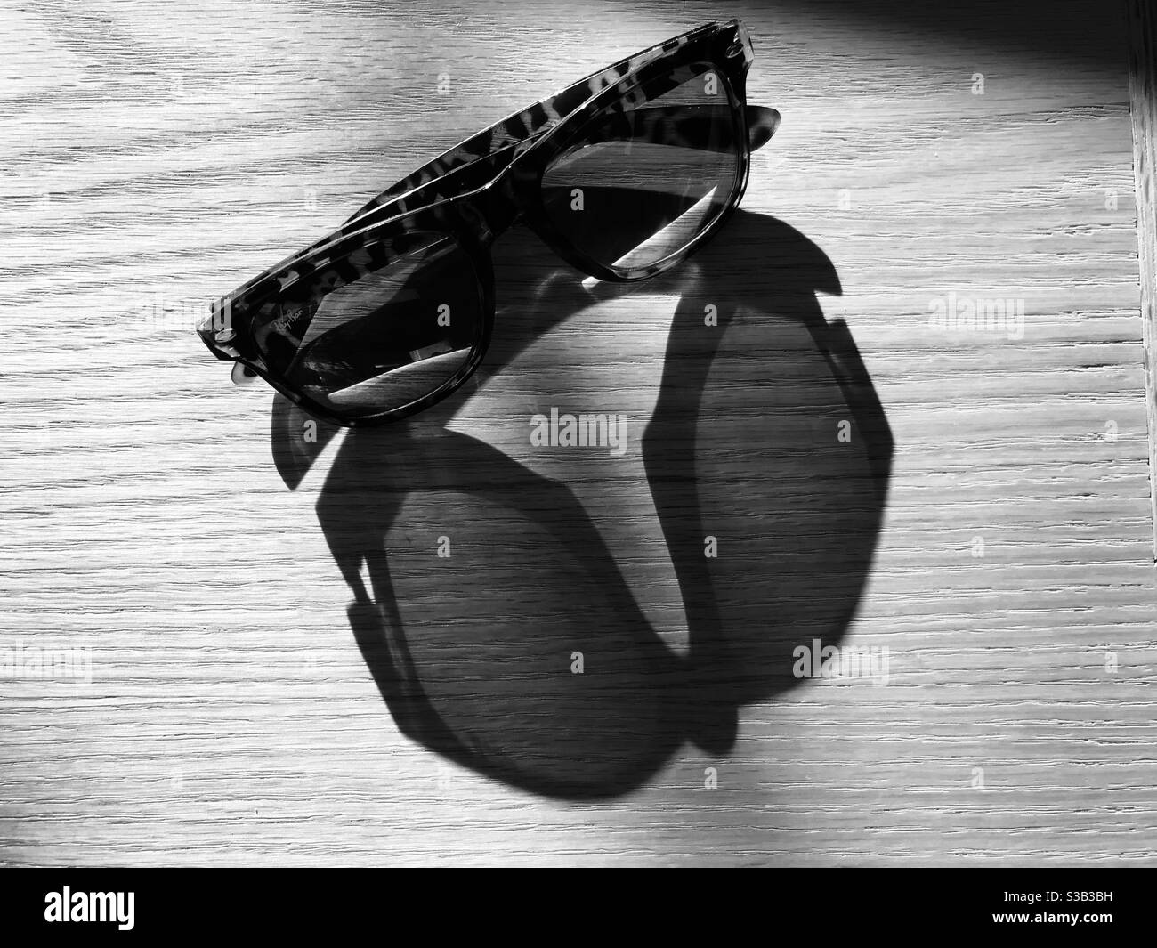 shadow of a dark glasses on a wooden table Stock Photo