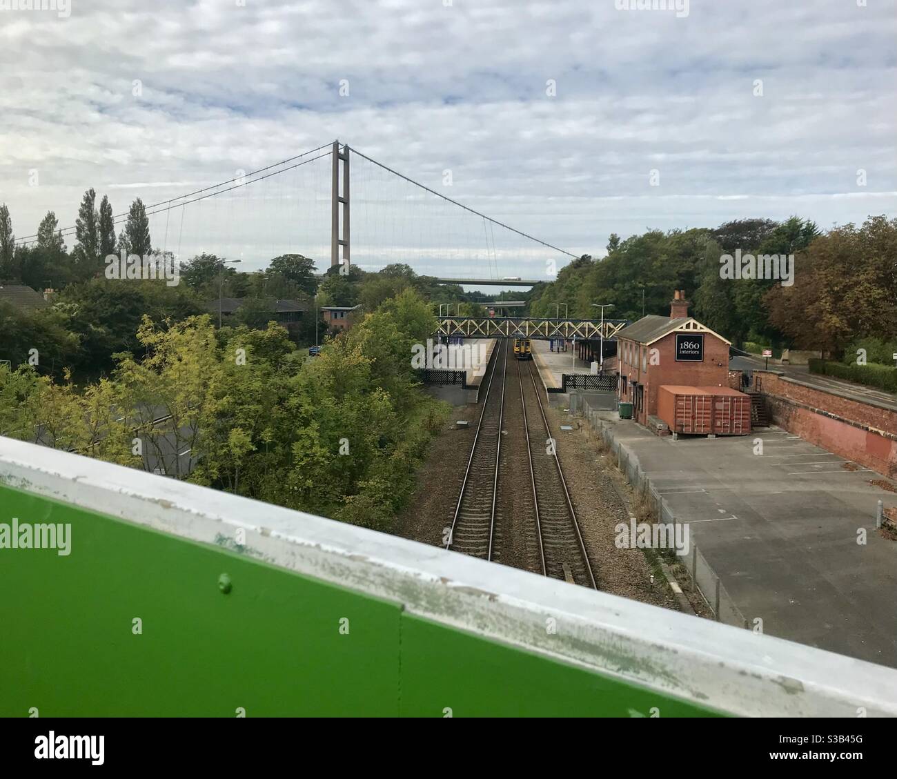 A train passes through Hessle station near Hull in East Yorkshire with the Humber Bridge in the background. Stock Photo