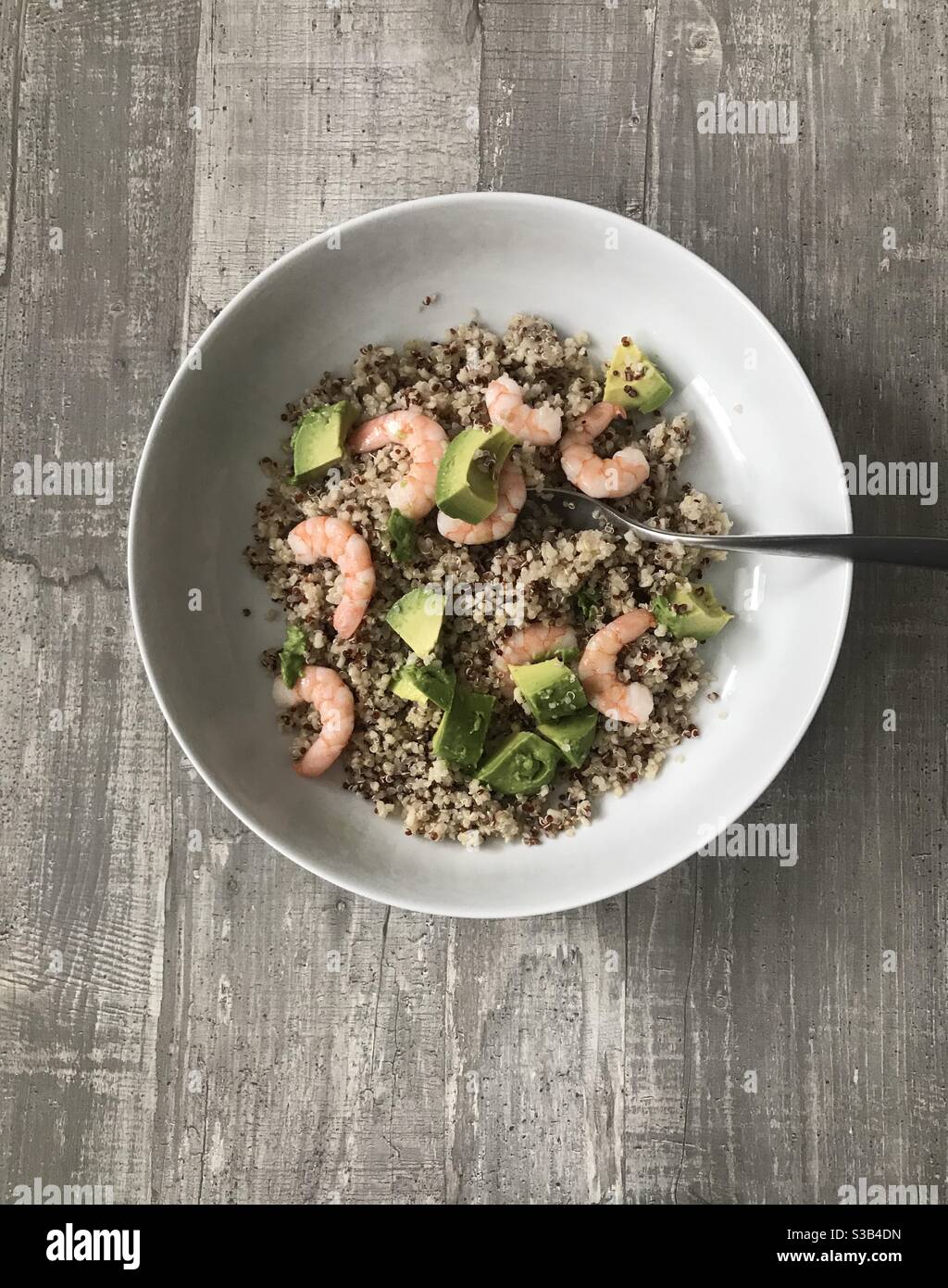 Red and white quinoa with fresh prawns and avocado against a wooden background - Smartphone Captured Stock Image
