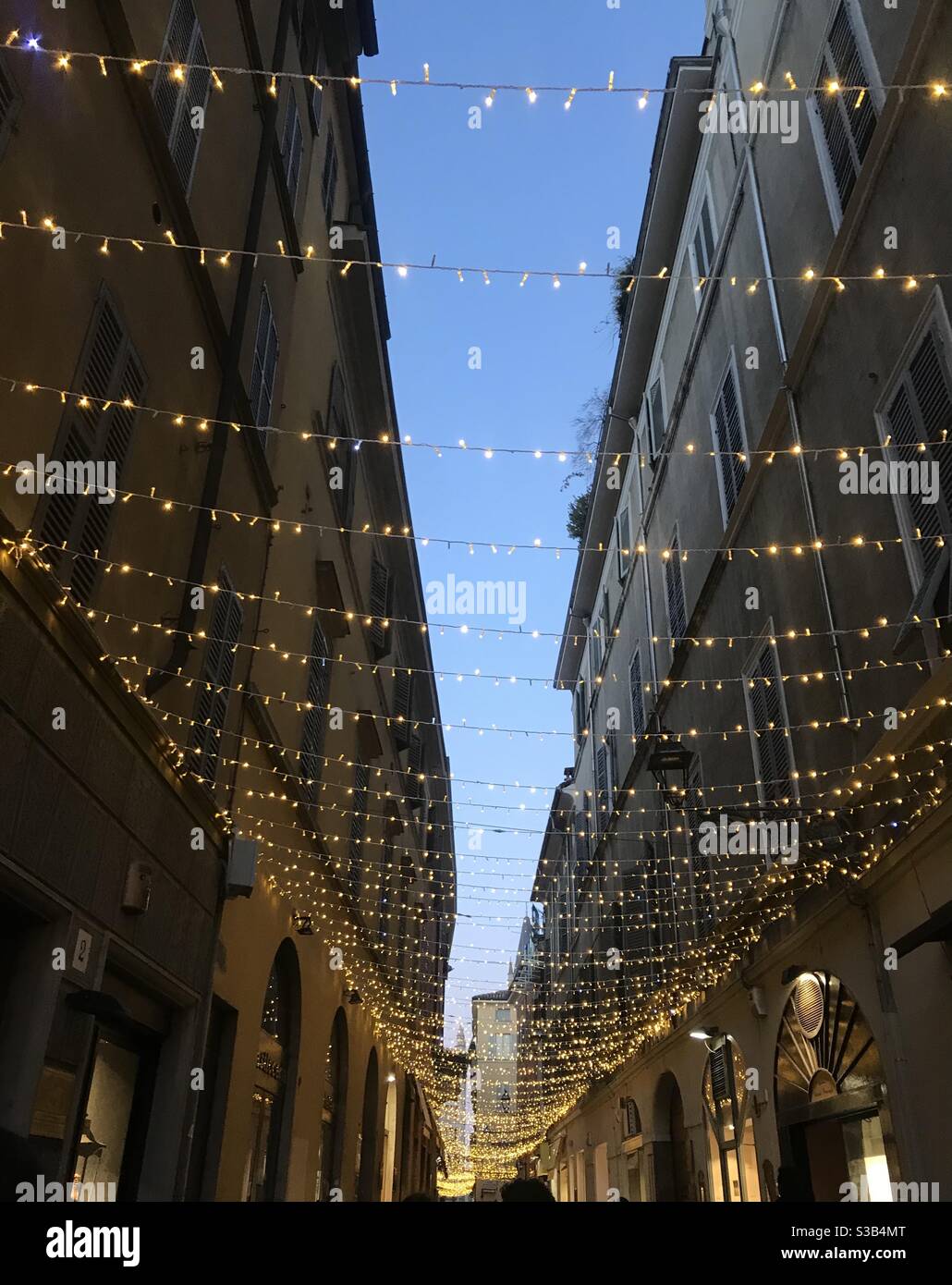 Christmas lights hanging between buildings in Parma city centre, Northern Italy - Smartphone Captured Stock Image