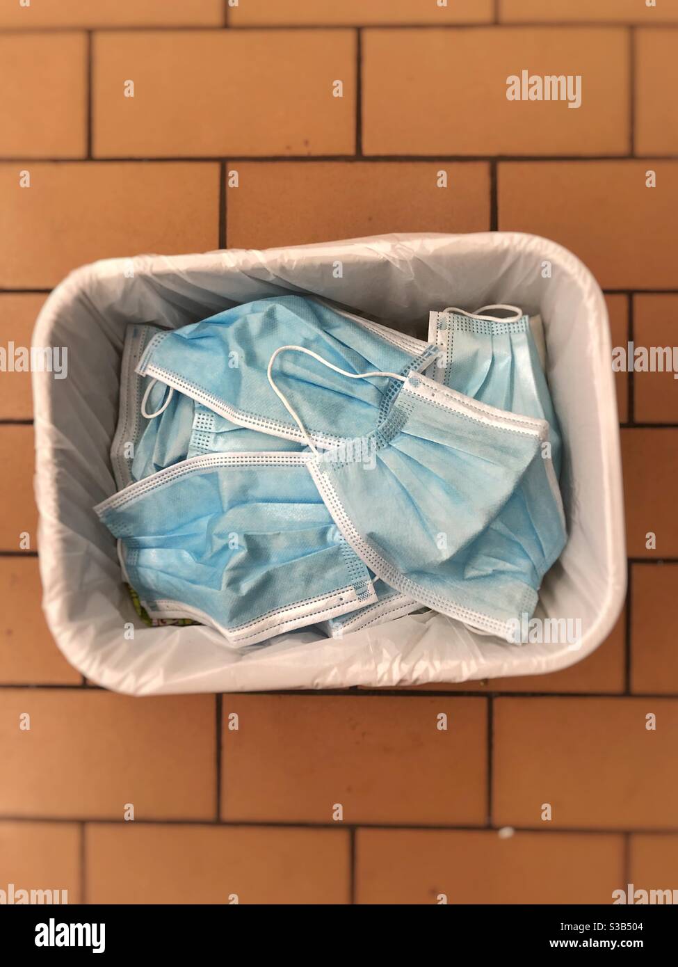 Trash basket full of single use face mask Stock Photo