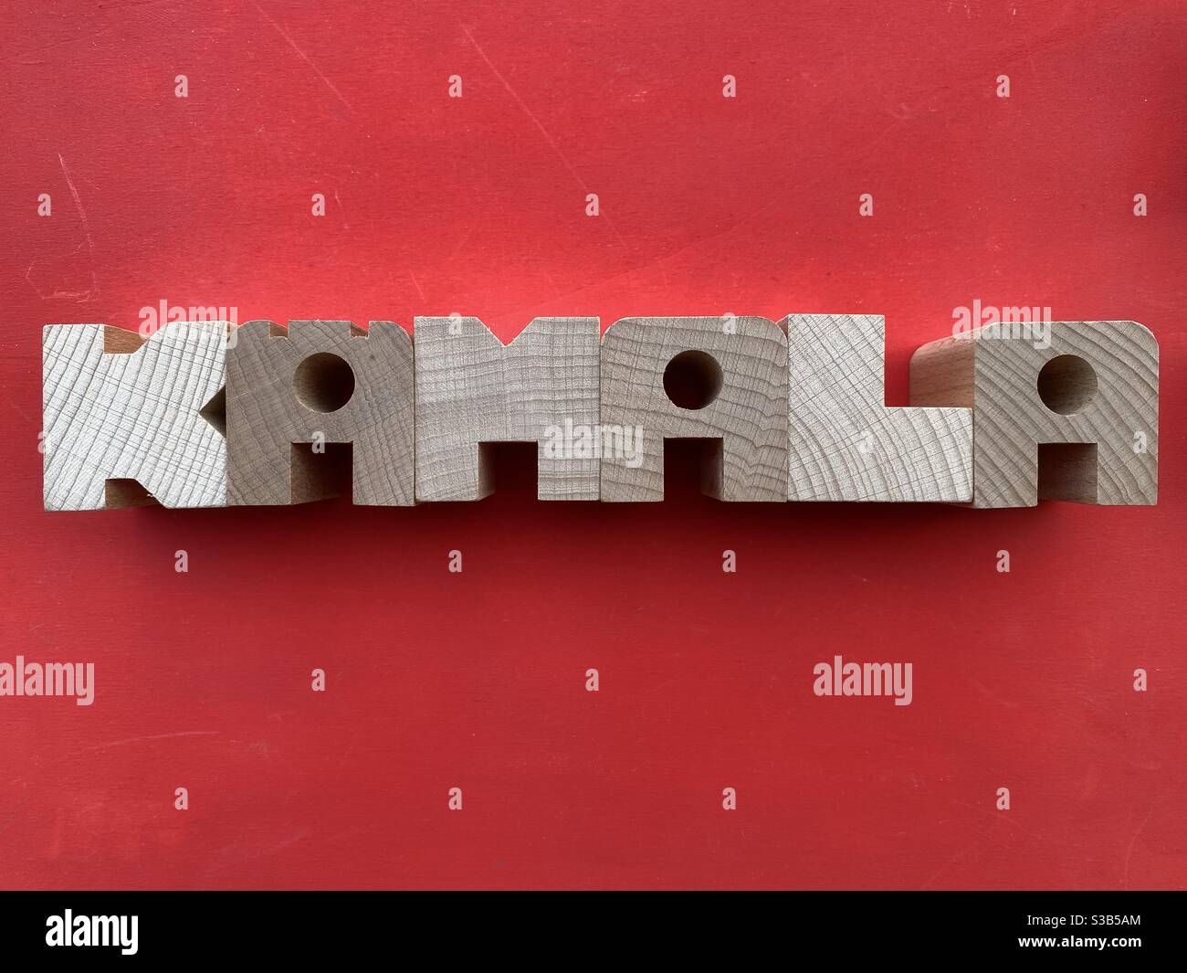 Kamala, female given name composed with wooden letters over red background Stock Photo
