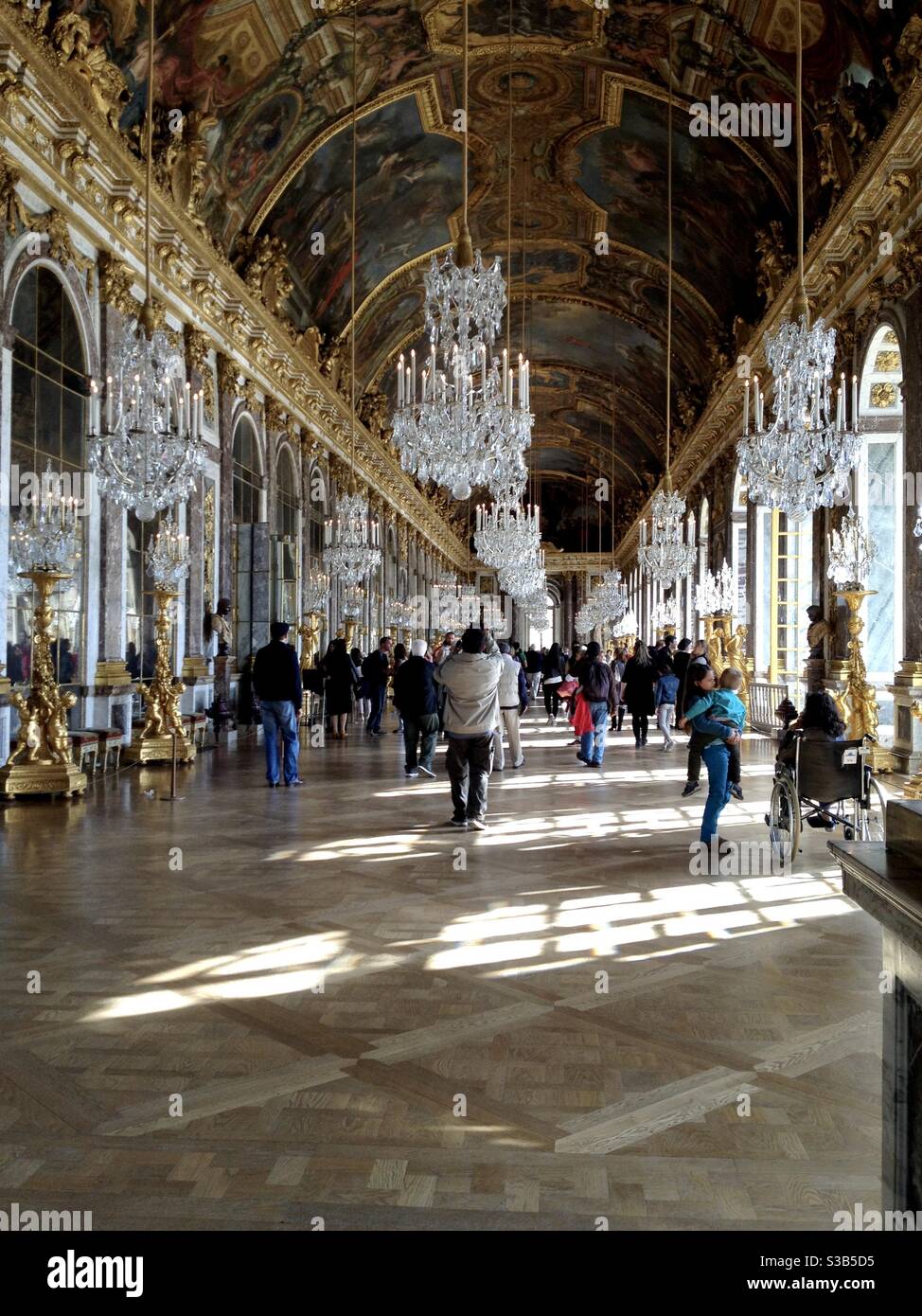 Tourists walking through the Hall of Mirrors at the palace of Versailles in Versailles, France. - Smartphone Captured Stock Image