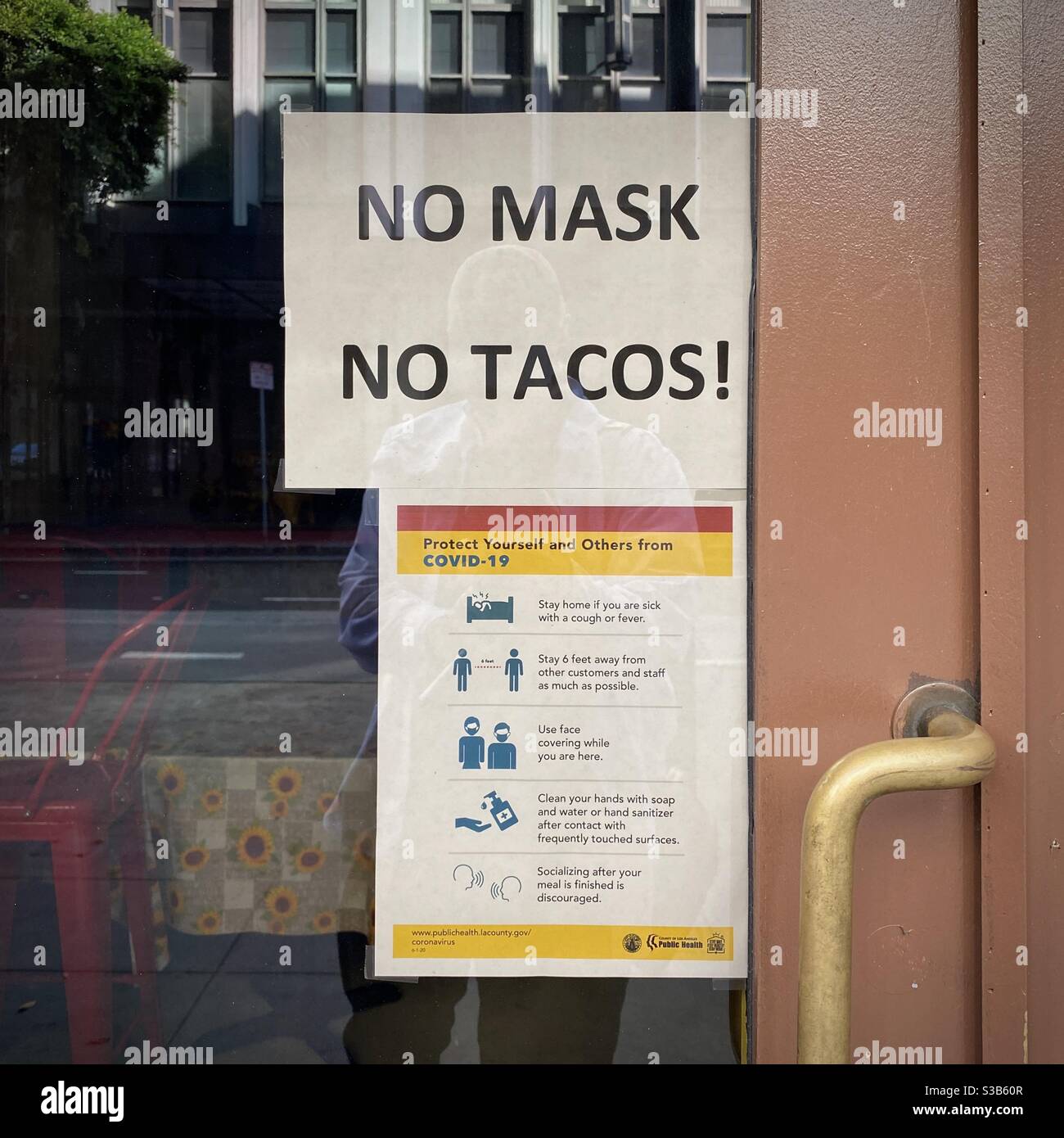 LOS ANGELES, CA, AUG 2020: 'No mask, No tacos!' sign and poster with information about Covid-19 on restaurant door in Downtown - Smartphone Captured Stock Image