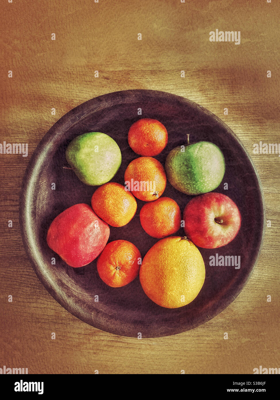 An overhead view of a wooden fruit bowl containing oranges, apples and tangerines. You can’t beat healthy fruit. 5 a day and all that?! Photo Credit ©️ COLIN HOSKINS. Stock Photo