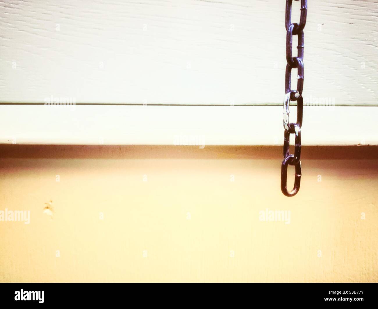 Chain hanging down in front of painted wooden drawer. - Smartphone Captured Stock Image