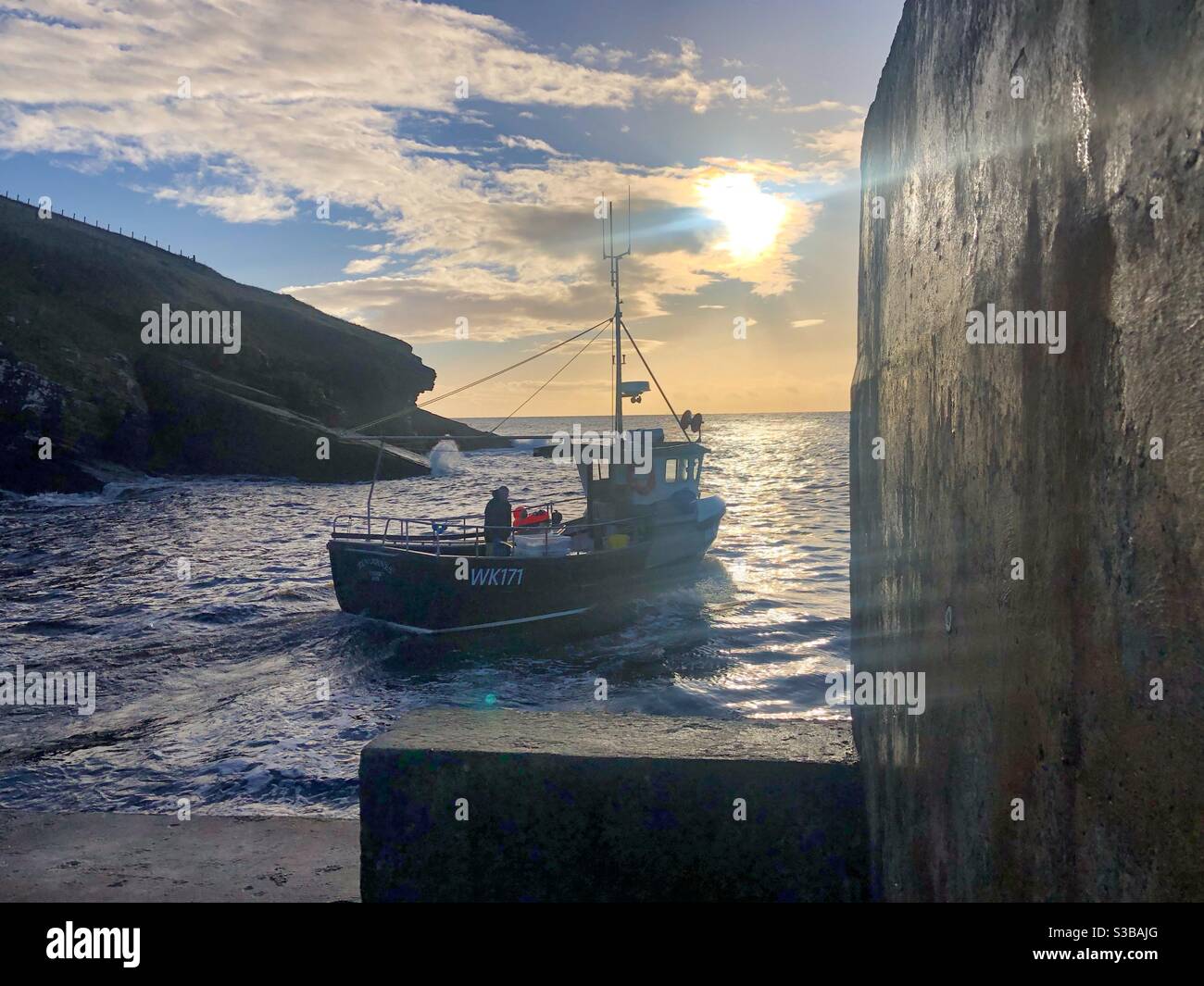 Fishing boat heading out into sunrise sea - Smartphone Captured Stock Image