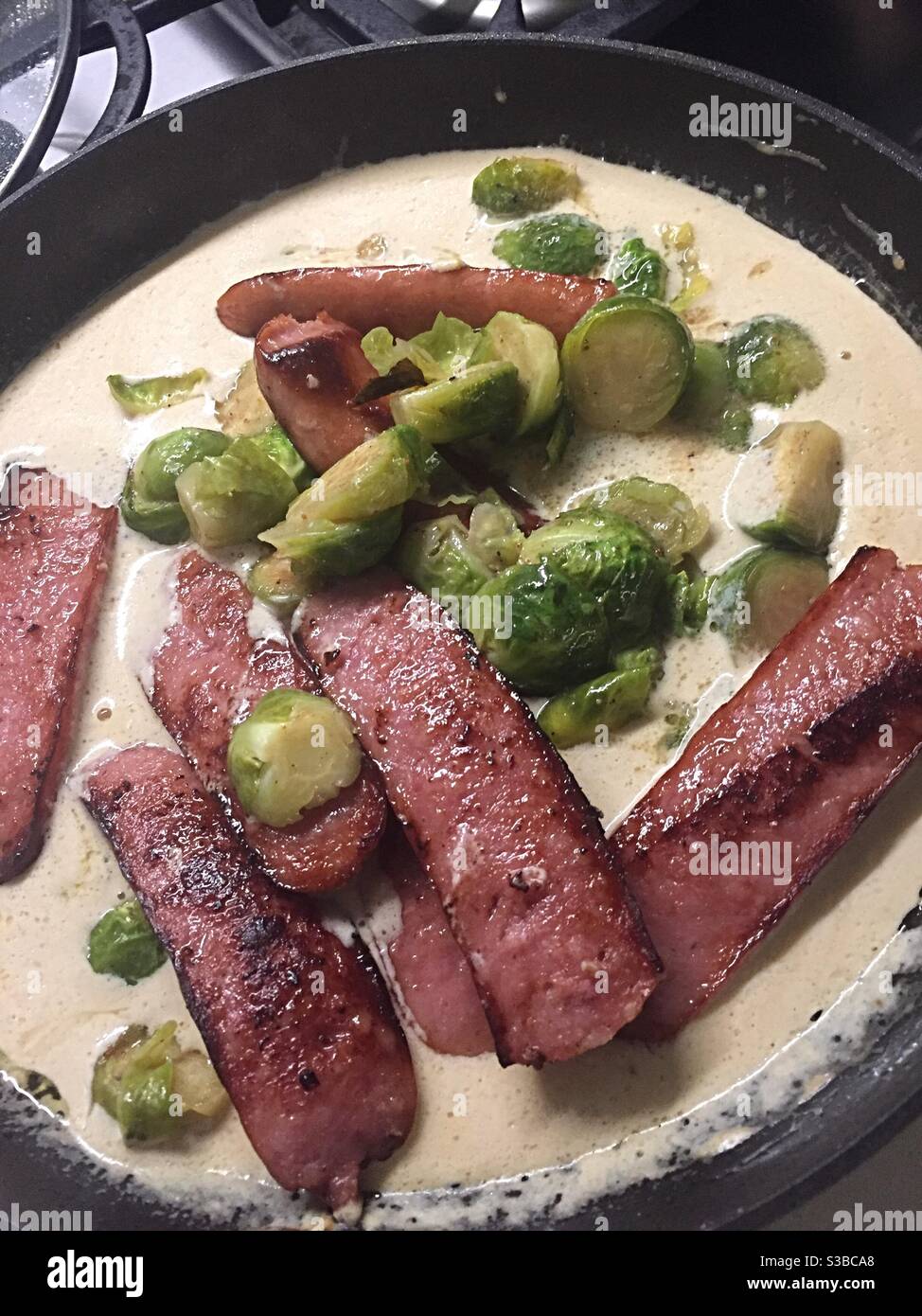 Close up of a one dish meal of brussels sprouts Poli sausage in a creamy mustard sauce in a stove top skillet - Smartphone Captured Stock Image