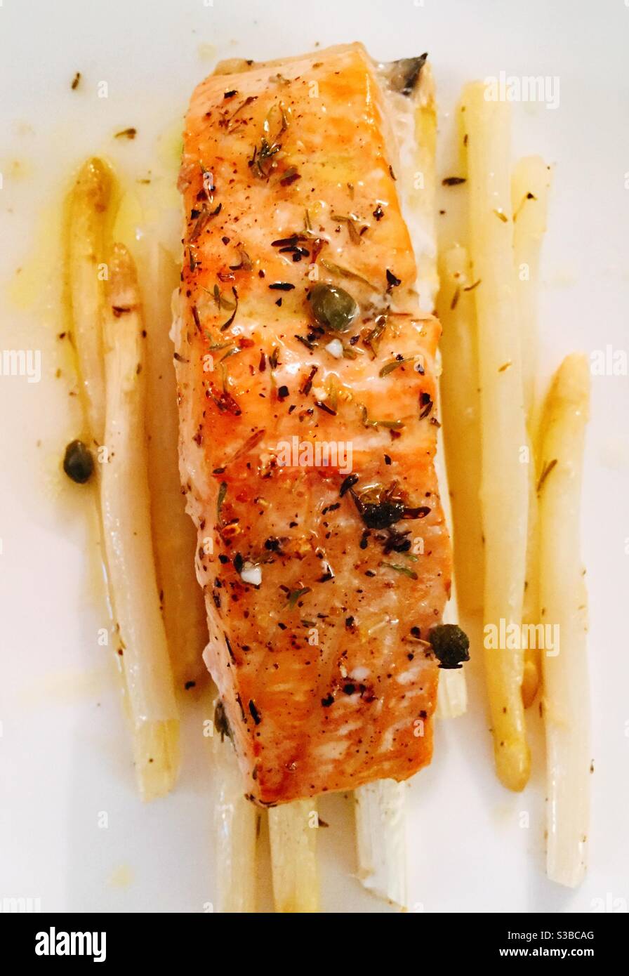Close-up detail of a baked salmon entrée on a bed of white asparagus on a white china plate, USA - Smartphone Captured Stock Image