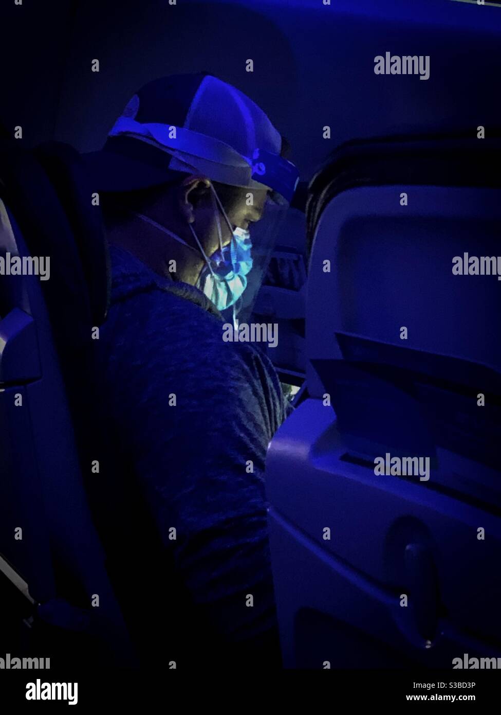 Portland, USA. 22nd Nov, 2020. Early in the evening a traveler over Oregon illuminated in the dark, wearing two surgeons masks and a face shield during the Covid-19 Pandemic. - Smartphone Captured Stock Image