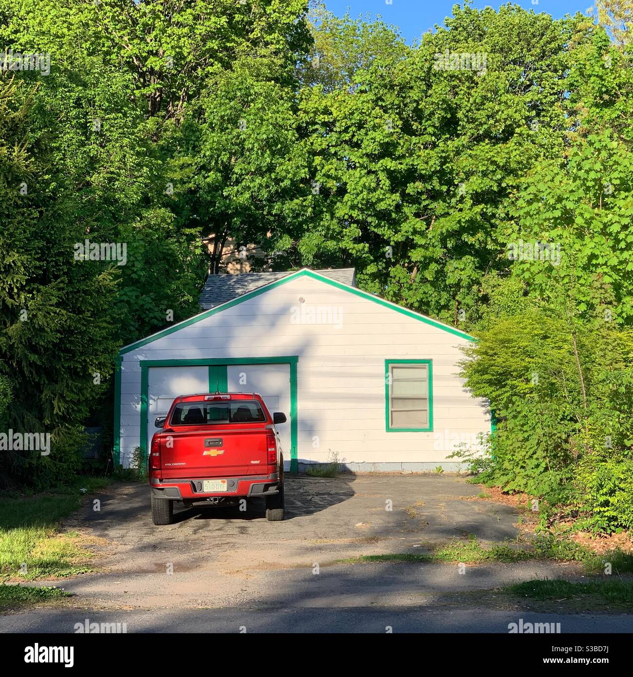 Red truck in front of a garage in Greenfield, Massachusetts, United States. Springtime, 2020. - Smartphone Captured Stock Image