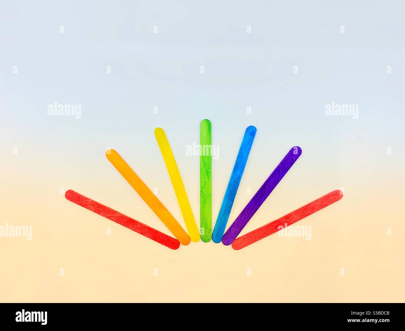 Rainbow coloured wooden sticks in a sun pattern. Sunrise concept. No people. Copy space. Stock Photo