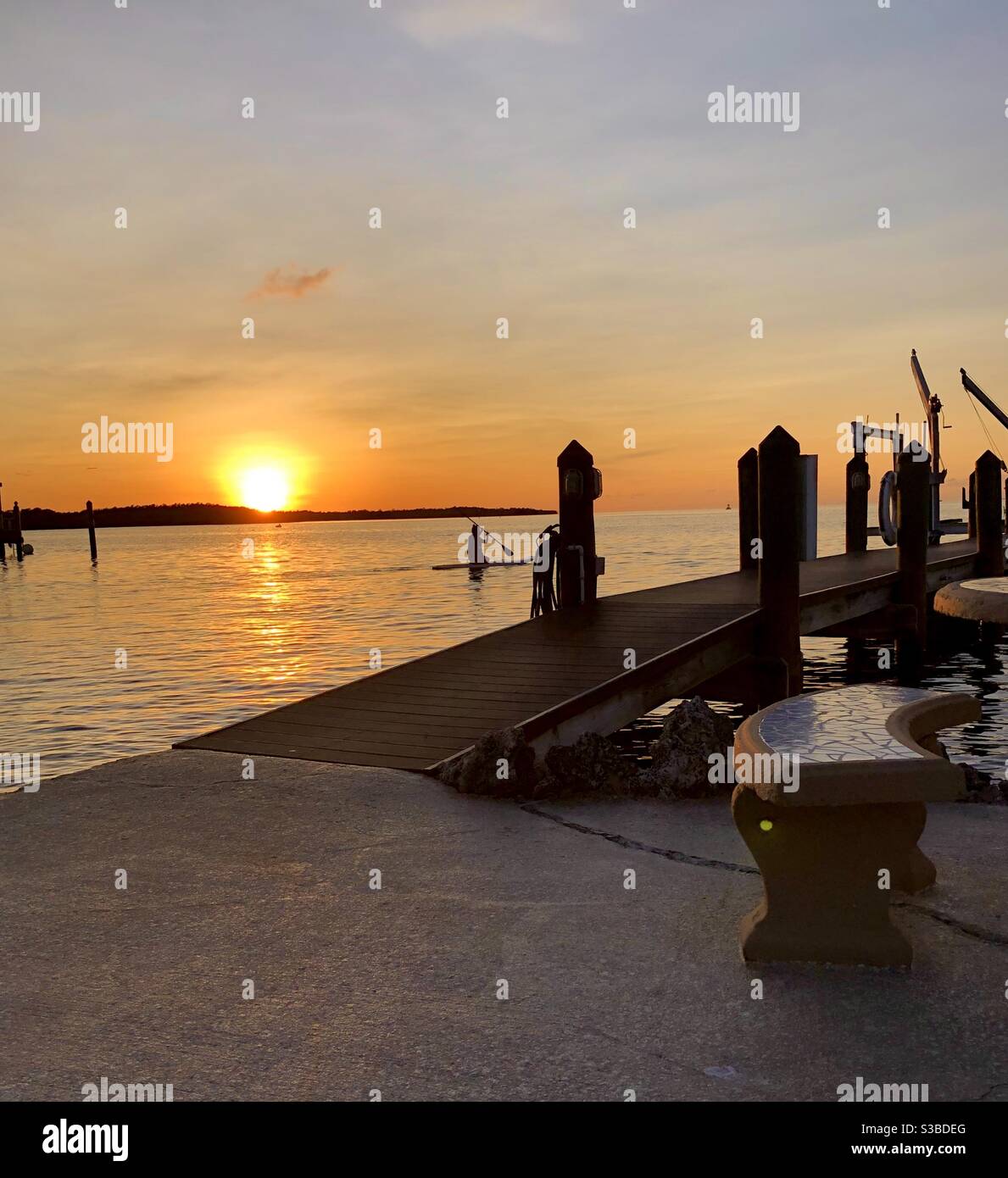Sun setting on the Bay along a dock with a person heading out on a paddle boat, Key Largo, Florida. Stock Photo