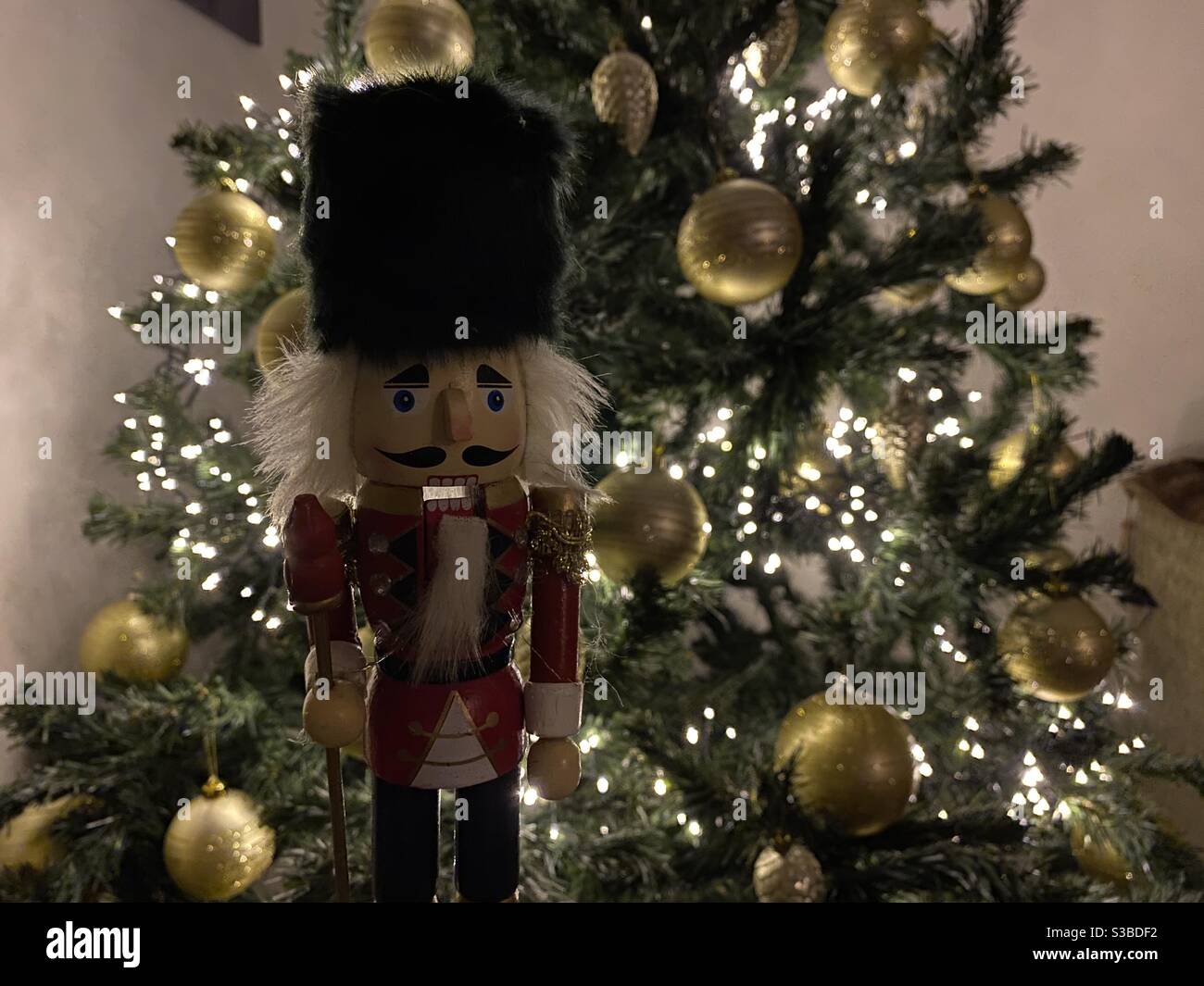 Traditional wooden toy standing in front of the Christmas tree. Stock Photo