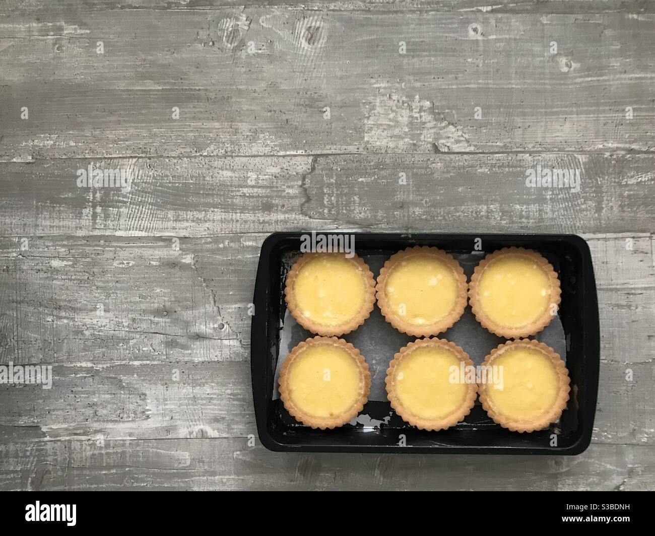 Individual lemon tartlets on a wooden background - Smartphone Captured Stock Image