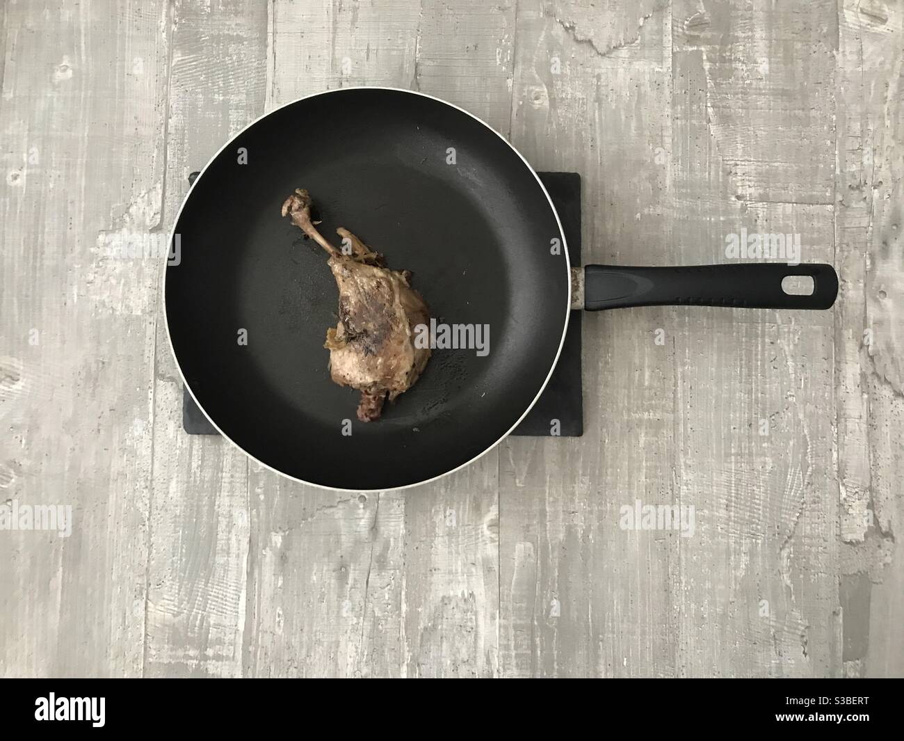 Pan fried confit duck leg on a wooden background Stock Photo