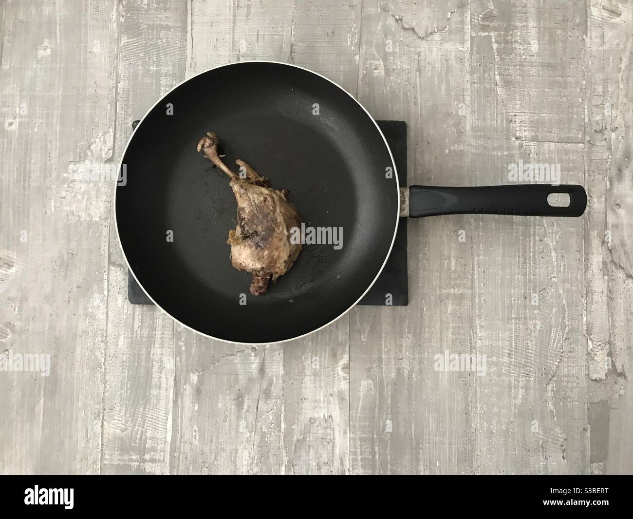 Pan fried confit duck leg on a wooden background - Smartphone Captured Stock Image