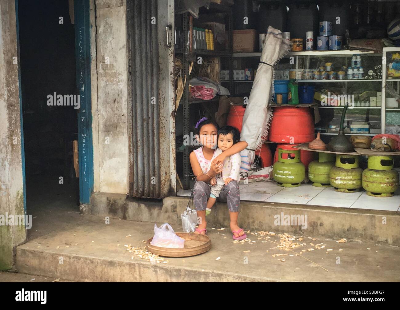 Two children in front of a family market shop in Bali Stock Photo