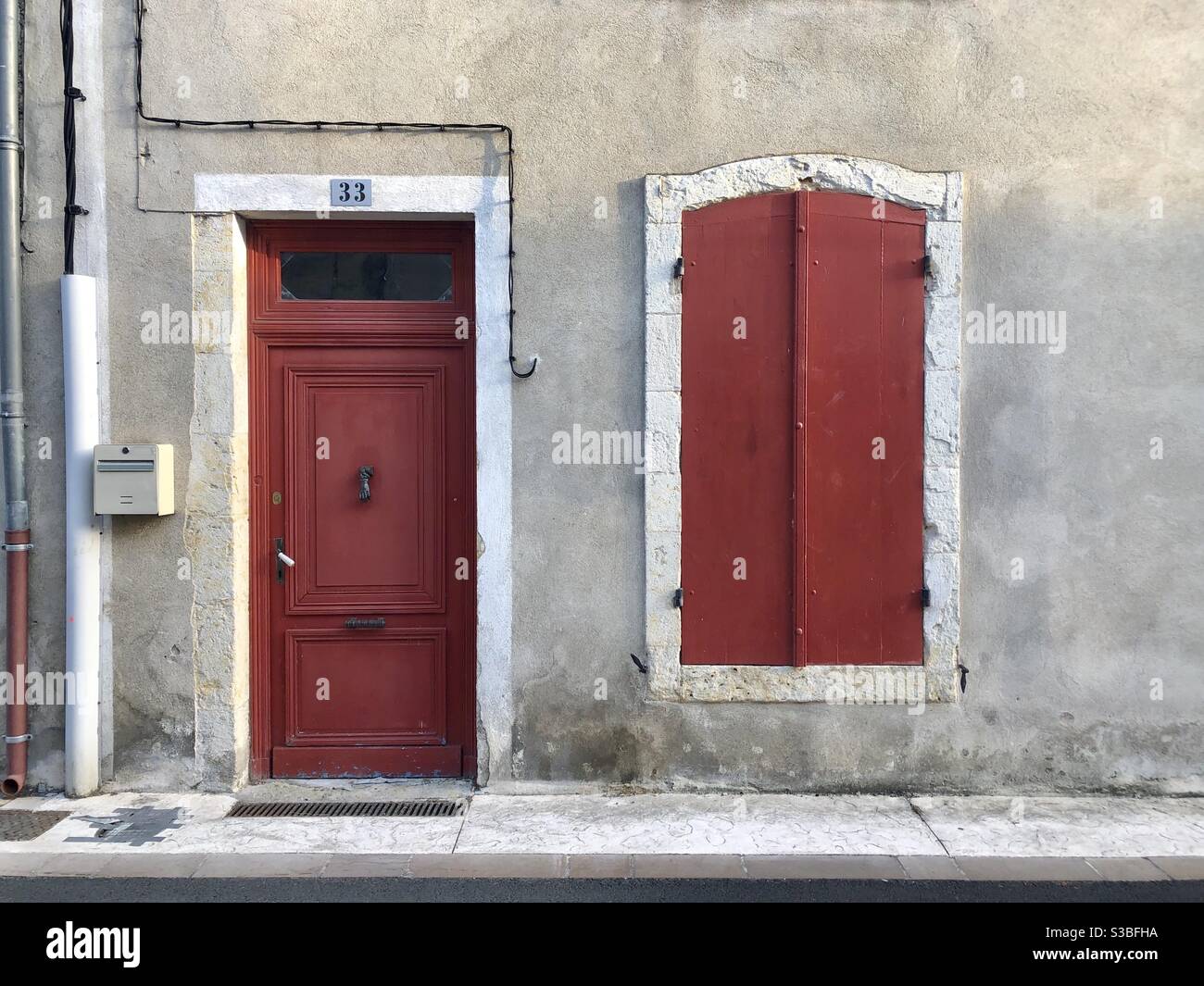 Exterior of town house in France with red painted wooden door and window shutters - Smartphone Captured Stock Image