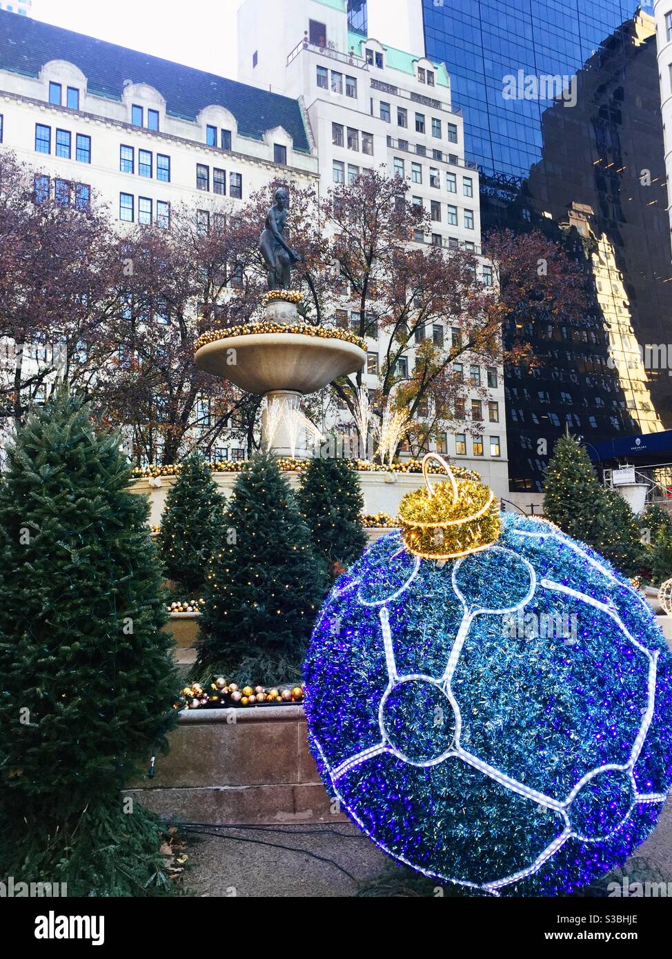 Pulitzer fountain outside of the Plaza Hotel in the grand Army Plaza features outsized Christmas ornaments and Christmas tree decorations during the holiday season - Smartphone Captured Stock Image