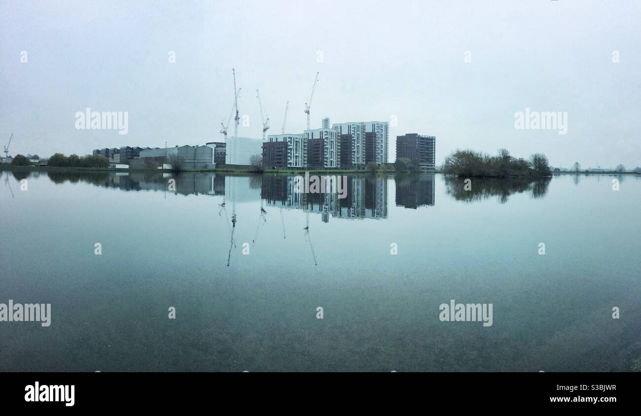 Looking across High Maynard reservoir to Higham Hill in Walthamstow, London. A grey winter day gives a perfect reflection to new housing developments - Smartphone Captured Stock Image