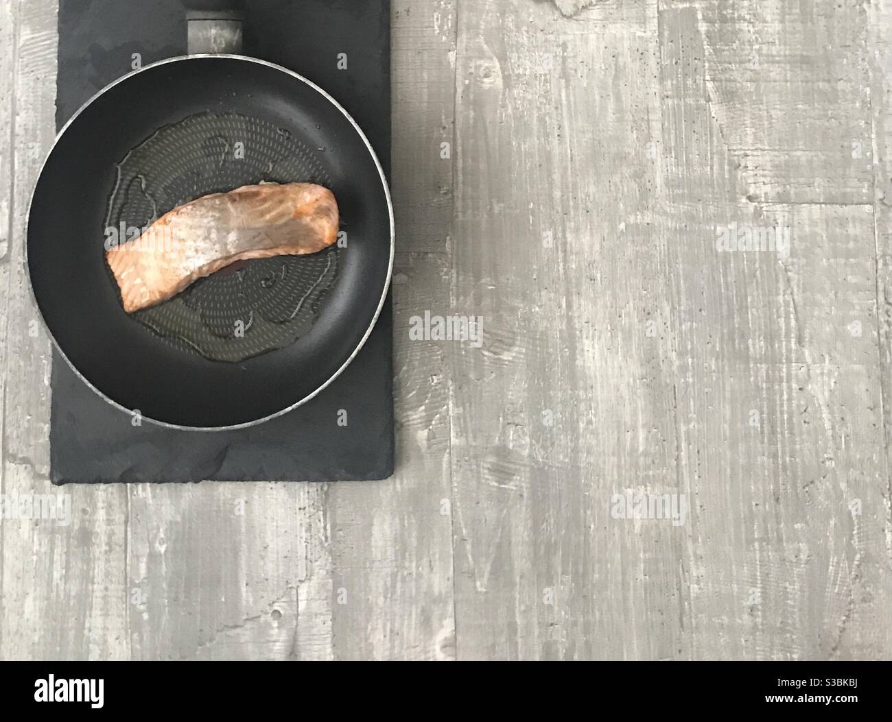 Fillet of salmon in a pan on a wooden background - Smartphone Captured Stock Image