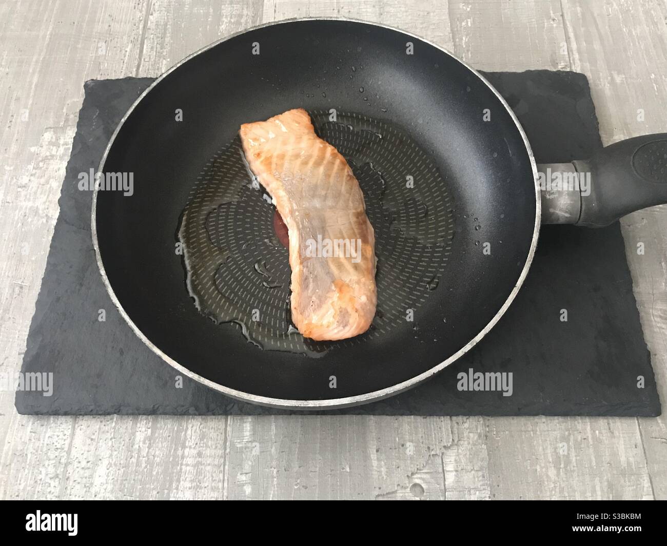 Fillet of salmon in a pan on a wooden background - Smartphone Captured Stock Image